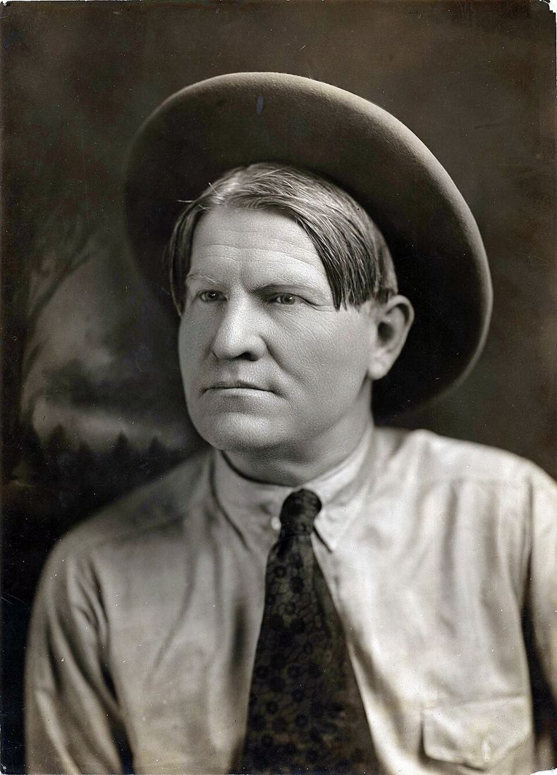 Portrait of artist Charles M. Russell seated in front of a painting, about 1900
