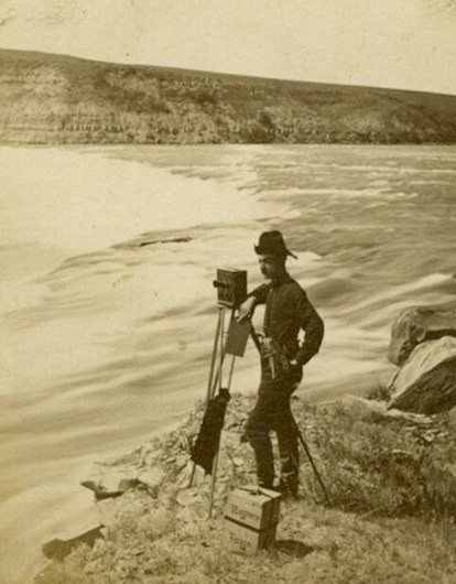 Photographer F. Jay Haynes standing beside his camera at the Great Falls of the Missouri River in 1880